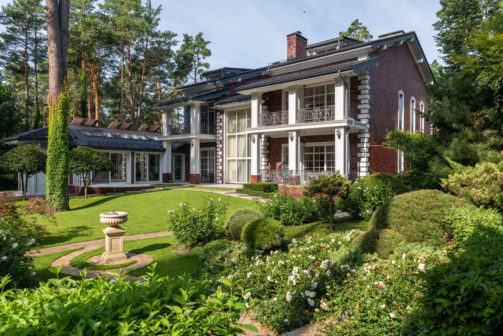 Family house with a formal garden of rounded shrubs, white roses and a stone birdbath